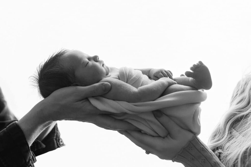 newborn photography in georgia, family photographers in georgia, atlanta area newborn photographers, best newborn photography atlanta, atlanta baby studio, buy buy baby photos, baby posed in mom and dads hands backlit, black and white newborn photos