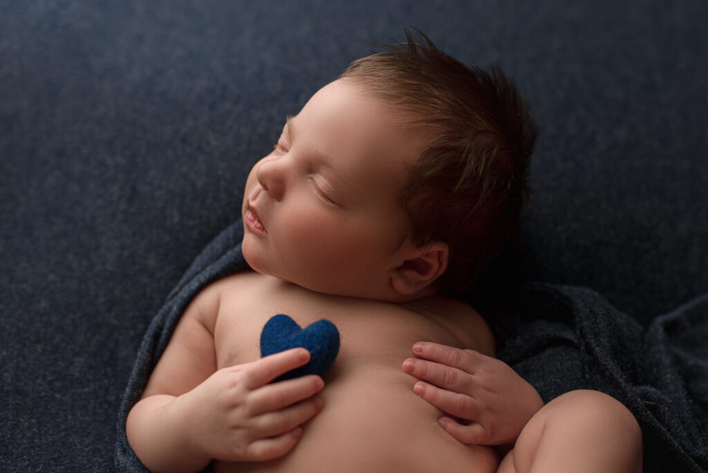 newborn boy posed on blue for his newborn photography session in lincoln nebraska, nebraksa newborn photographer, in home newborn session near me