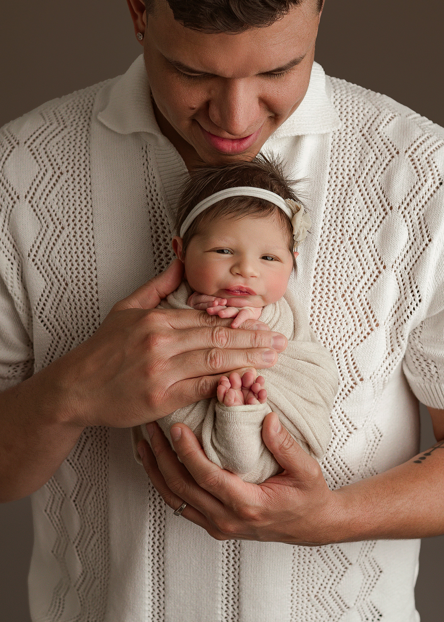 BFP_19541 awake baby girl with floral headband in dads hands, captured by Nebraska newborn photographer